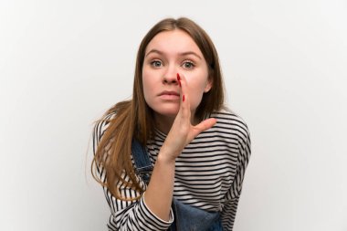 Beyaz duvarın üzerinde dungarees genç kadın bir şey fısıldıyor