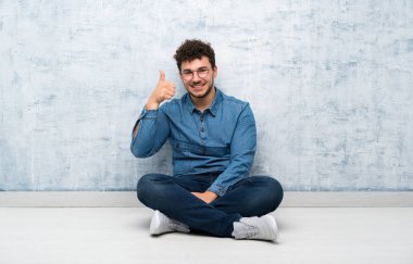 Gözlükle yerde oturan genç adam