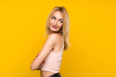Genç Sarışın kadın üzerinde izole sarı duvar gülüyor