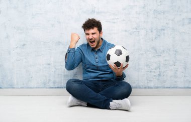 Yerde futbol topu tutan genç adam