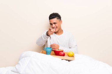 Yatakta kahvaltı olan genç adam seni parmak