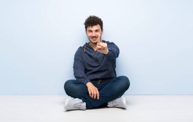 Genç adam yerde oturuyor ve parmağını kaldırıyor.