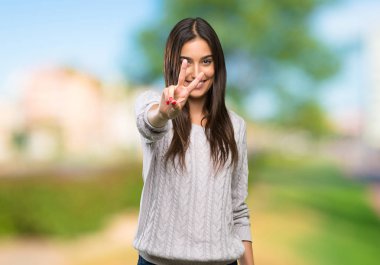 Genç İspanyol esmer kadın gülümseyen ve açık havada zafer işareti gösteren