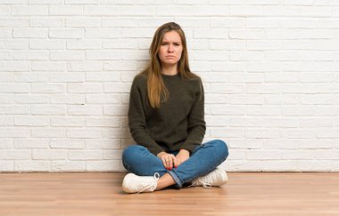 Üzgün ve depresif ifade ile yerde oturan genç kadın