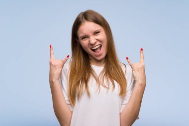 Mavi duvar üzerinde rock jesti yapan genç kadın