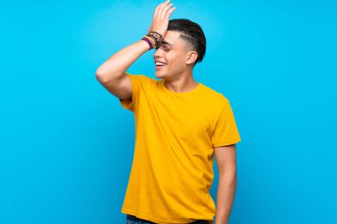 Izole mavi arka plan üzerinde sarı gömlek li genç adam bir şey fark etti ve çözüm niyetinde