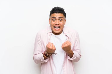 Genç adam bir zaferini kutluyor izole beyaz duvar üzerinde