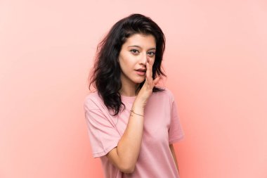 Izole pembe arka plan üzerinde genç kadın bir şey fısıldıyor