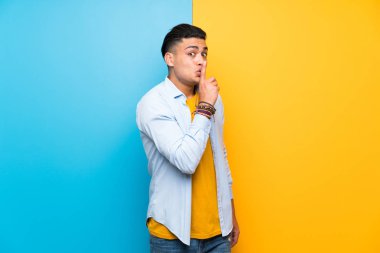 Izole renkli arka plan üzerinde sessizlik jest yapıyor genç adam