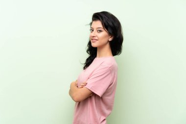 Kolları geçti ve ileriye bakan izole yeşil arka plan üzerinde genç kadın