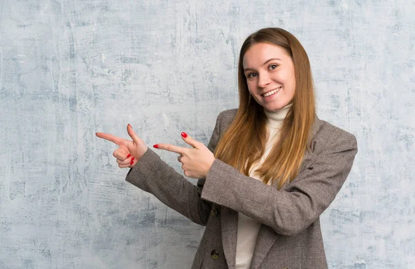 Mladá Žena Grungeové Stěně Ukazující Prstem Stranu — Stock fotografie