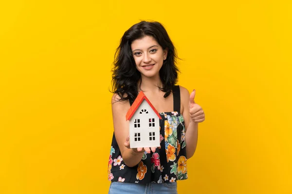 Mujer Joven Sobre Fondo Amarillo Aislado Sosteniendo Una Casita —  Fotos de Stock