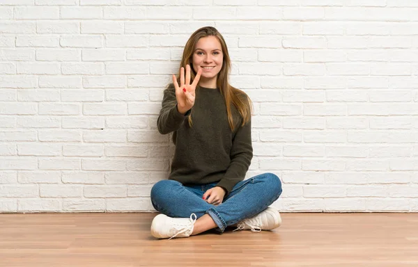 Νεαρή Γυναίκα Κάθεται Στο Πάτωμα Ευτυχισμένη Και Μετρώντας Τέσσερις Δάχτυλα — Φωτογραφία Αρχείου