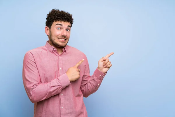 Homem Com Cabelo Encaracolado Sobre Parede Azul Isolada Assustado Apontando — Fotografia de Stock