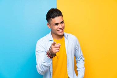 Izole renkli arka plan noktaları üzerinde genç adam size parmak