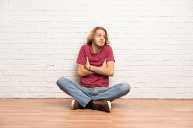 Sarışın adam omuzlarını kaldırırken şüphe jest ilerler ken yerde oturan