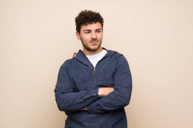 Karışık yüz ifadesi ile izole duvar üzerinde kıvırcık saçlı adam