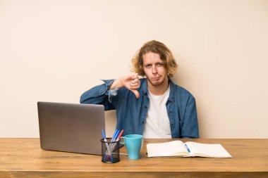 Başparmak aşağı işareti gösteren bir dizüstü bilgisayar ile Sarışın adam