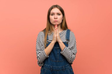 Pembe duvar üzerinde tulum ile genç kadın birlikte palmiye tutar. Kişi bir şey ister