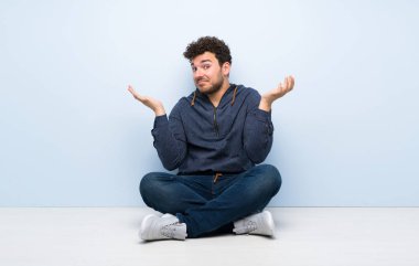 Açık kat yapma oturan genç adam jest şüphe ediyor.