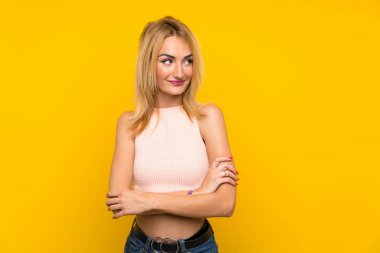 Genç Sarışın kadın üzerinde izole sarı duvar düşünme bir fikir