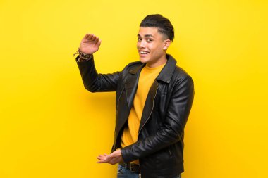 Bir reklam eklemek için copyspace tutan izole sarı arka plan üzerinde genç adam