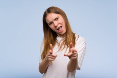 Genç kadın önüne işaret ve gülümseyen mavi duvarın üzerinden