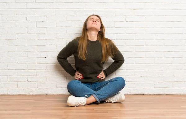 Junge Frau Sitzt Auf Dem Boden Und Leidet Unter Rückenschmerzen — Stockfoto