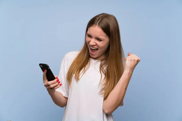 Junge Frau Über Blaue Mauer Feiert Sieg Mit Handy — Stockfoto