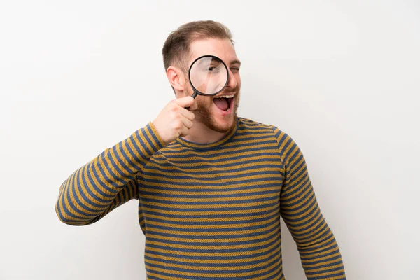 Hombre Guapo Sobre Una Pared Blanca Aislada Sosteniendo Una Lupa — Foto de Stock