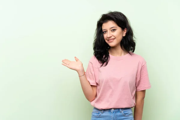 Jonge Vrouw Geïsoleerde Groene Achtergrond Houden Copyspace Denkbeeldig Palm Een — Stockfoto