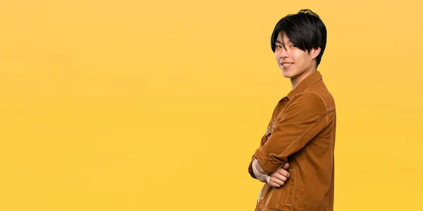 Asian Man Brown Jacket Arms Crossed Looking Forward Isolated Yellow — Stock Photo, Image