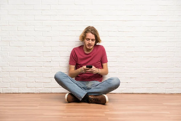 Homem Loiro Sentado Chão Enviando Uma Mensagem Com Celular — Fotografia de Stock
