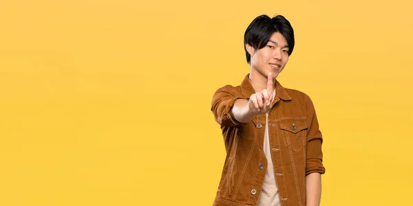 Asian Man Brown Jacket Showing Lifting Finger Isolated Yellow Background — Stock Photo, Image