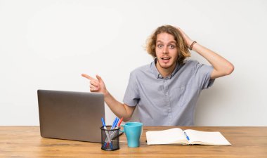 Bir dizüstü bilgisayar ile Sarışın adam şaşırttı ve yan parmak işaret