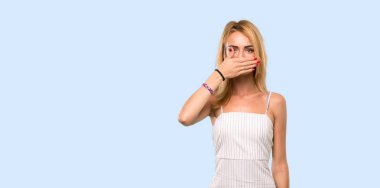 Genç sarışın kadın izole mavi arka plan üzerinde elleri ile ağız kapsayan