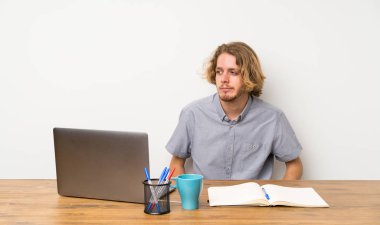 Bir dizüstü bilgisayar ile Sarışın adam yan görünümlü şüpheler jest yapma