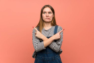 Pembe duvar üzerinde tulum ile genç kadın şüpheleri olan laterals işaret