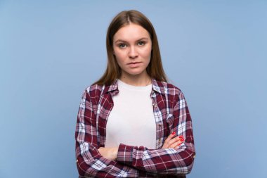 Kollarını çapraz tutan mavi duvar üzerinde genç kadın