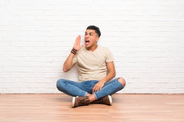 Yerde oturan genç adam ağzı tamamen açık bağırarak