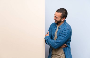 Kolombiyalı adam yan bakarak boş bir plasard tutan