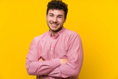 İzole sarı duvar üzerinde kıvırcık saçlı adam gülüyor