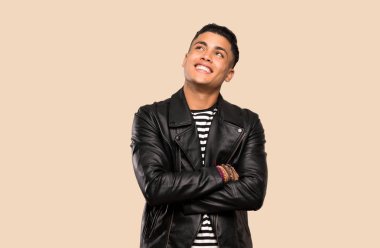 İzole arka plan üzerinde gülümseyen genç adam yukarı bakıyor