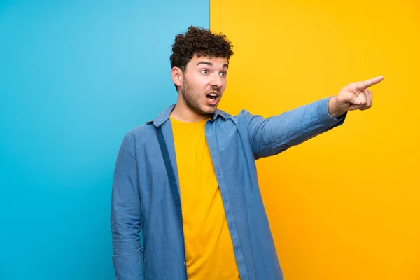 Homme Aux Cheveux Bouclés Sur Mur Coloré Pointant Vers Extérieur — Photo