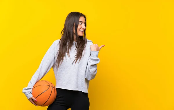Young Woman Playing Basketball Isolated Yellow Background Pointing Side Present — Stock Photo, Image