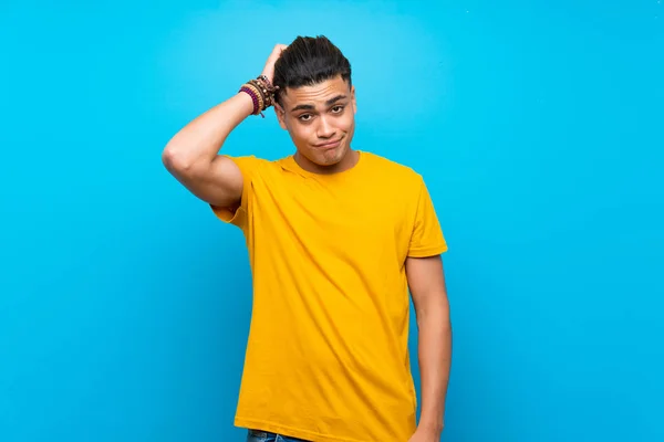 Young man with yellow shirt over isolated blue background with an expression of frustration and not understanding