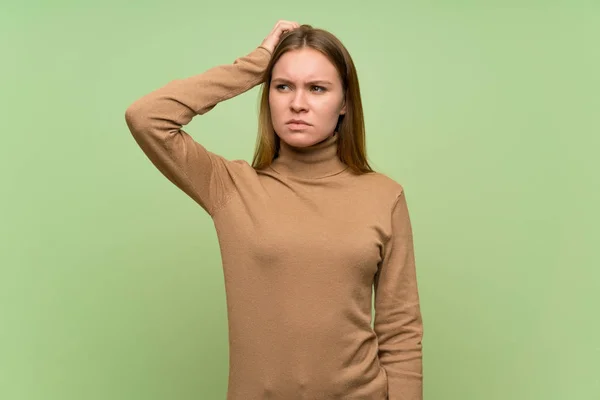 Young woman with turtleneck sweater having doubts while scratching head