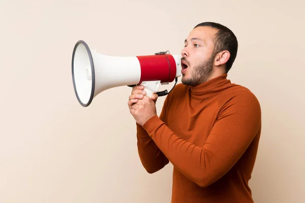 Colombian man with turtleneck sweater shouting through a megaphone