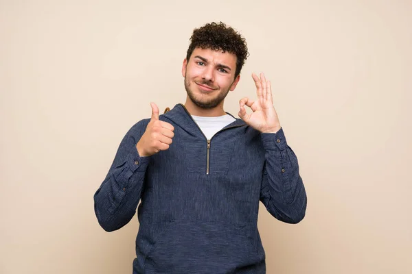 Człowiek Kręcone Włosy Izolowanej Ścianie Pokazując Znak Kciuka Górę Gest — Zdjęcie stockowe