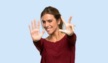 Sarışın kadın izole mavi arka plan üzerinde parmakları ile yedi sayma